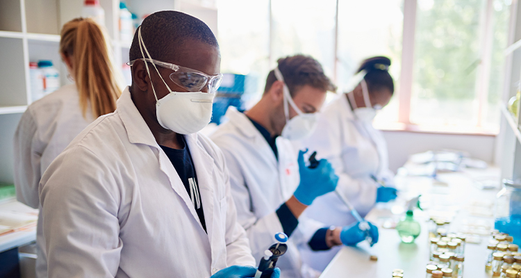 A diverse group of laboratory workers in protective gear preparing samples